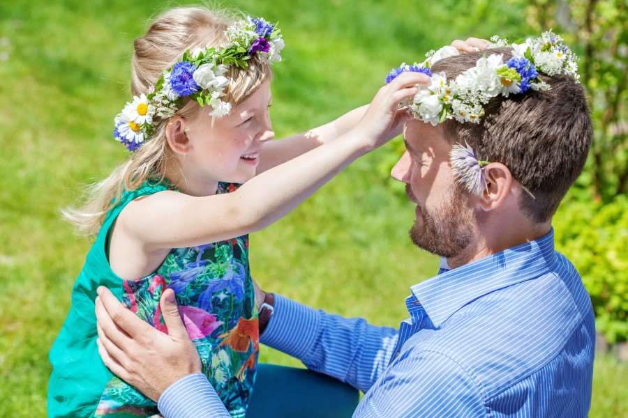 Ett barn sätter en midsommarkrans på en vuxen.