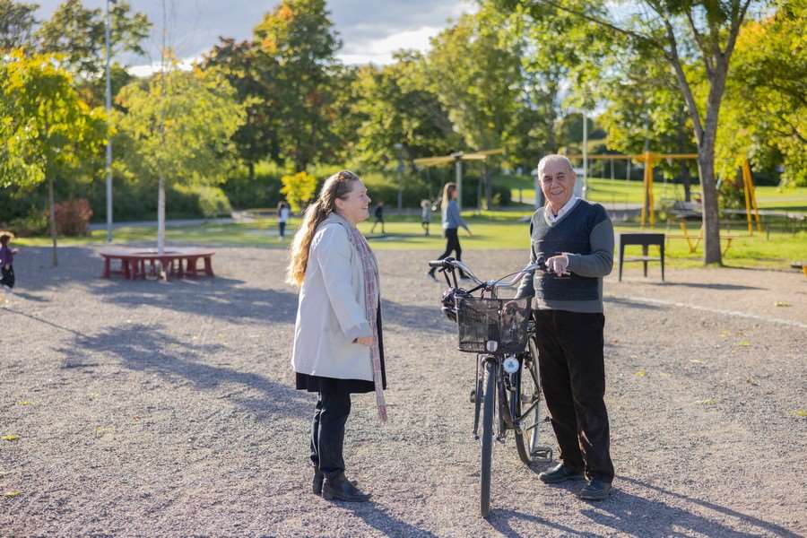 Kvinna pratar med man med cykel i park