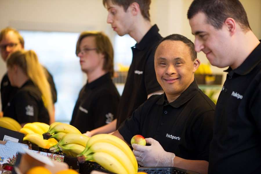 Unga glada män plockar med frukt