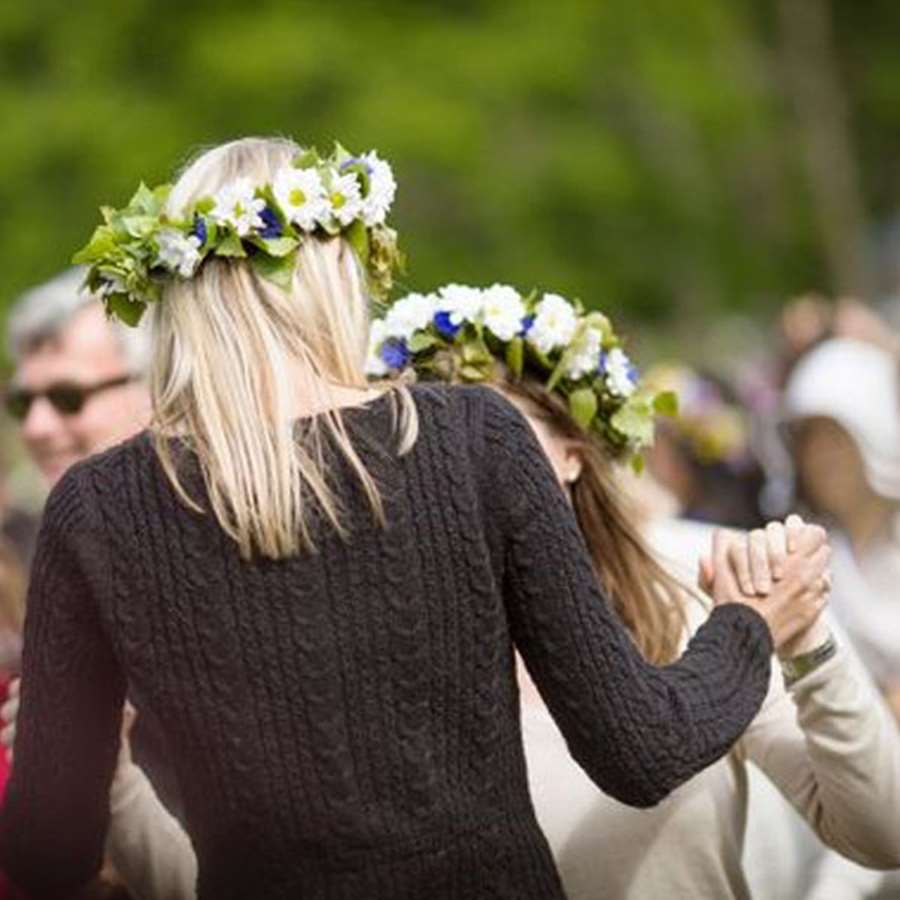 Människor dansar med midsommarkransar i håret.