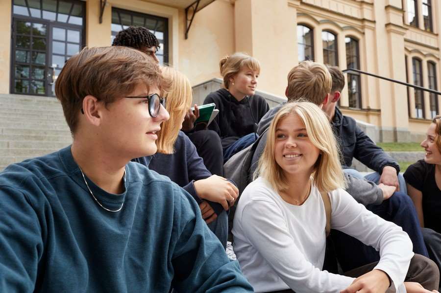 Ungdomar sitter på en trappa och pratar med varandra