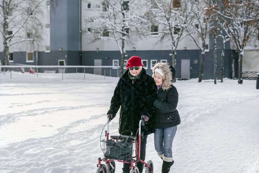 Dam med rollator och följeslagare