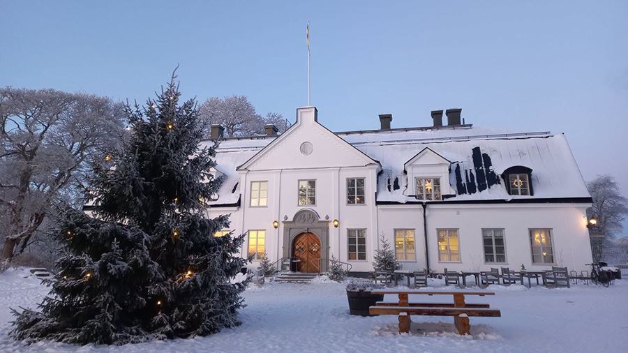 Vit herrgårdsbyggnad med en julgran framför