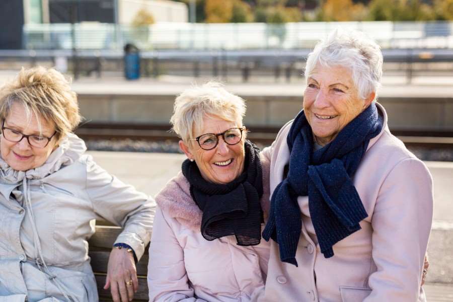 Tre glada personer på en tågperrong