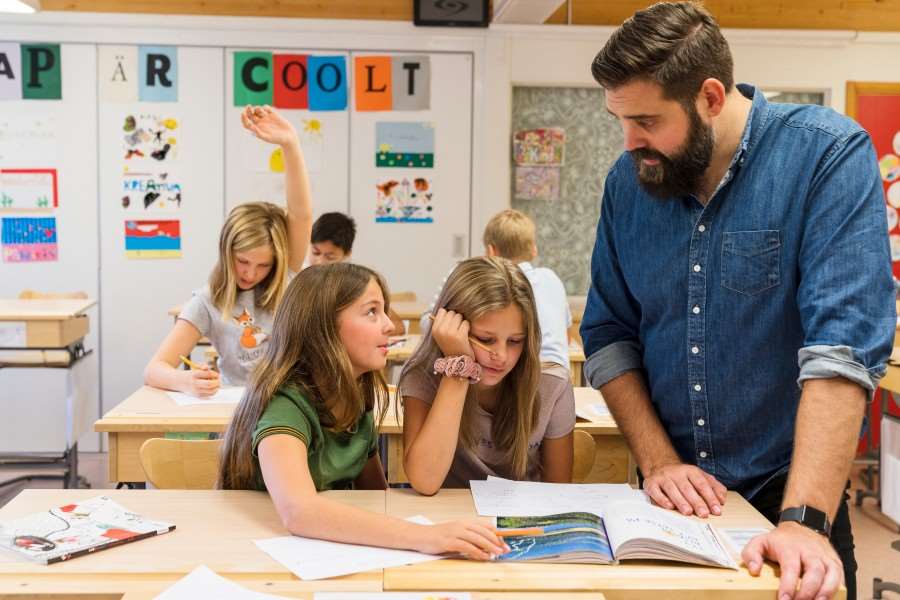 Lärare hjälper två elever i ett klassrum.