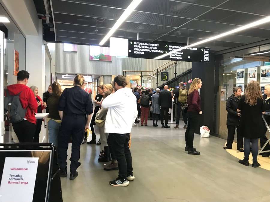 Samling människor står runt bord och disskuterar