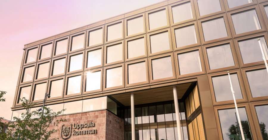 En husfasad som reflekterar solen. Texten Uppsala kommun står på fasaden.