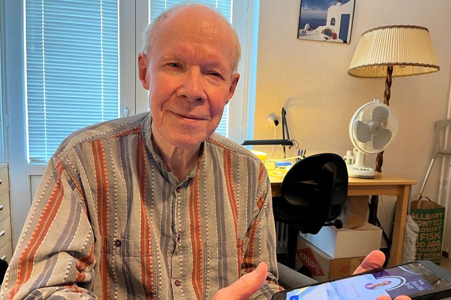 En man i randig skjorta håller i en surfplatta