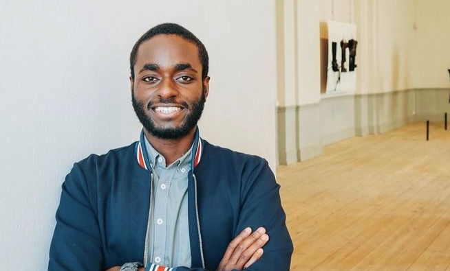 Man som står med armarna i kors och ler