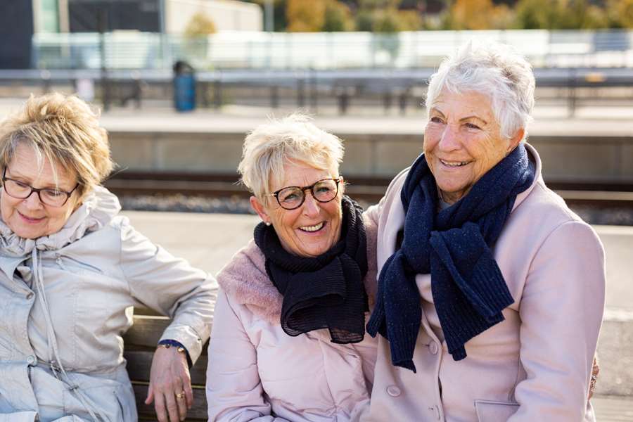 Tre medelålders kvinnor skrattar mot kameran.