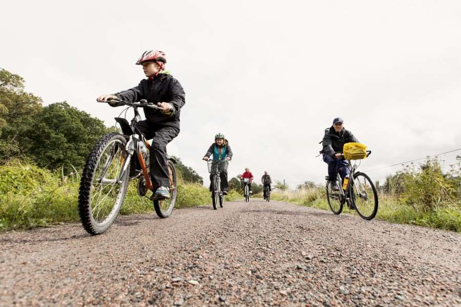 Barn och vuxna cyklar på grusväg