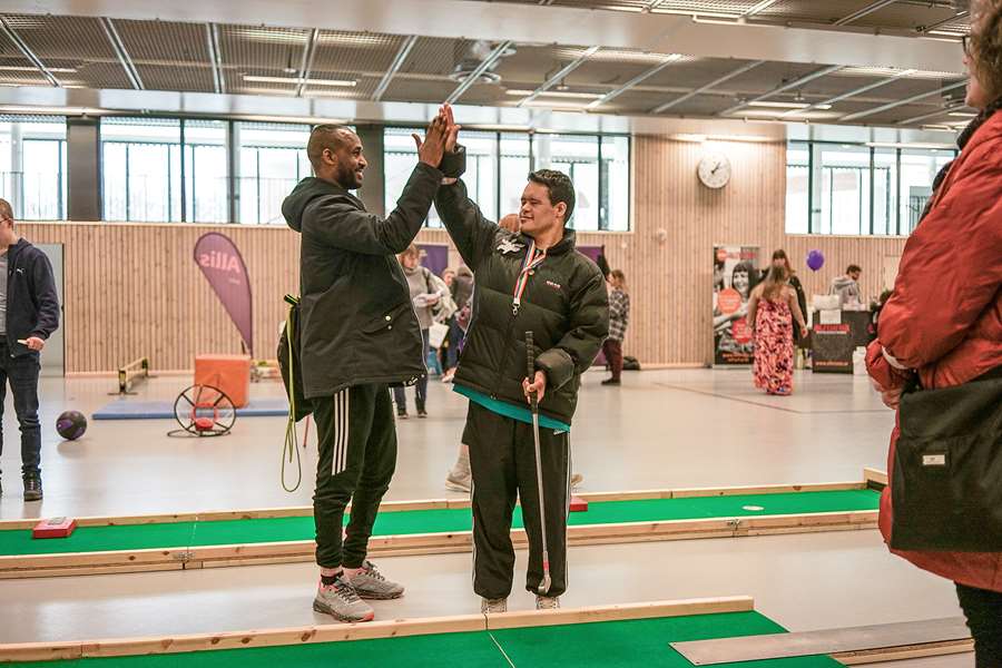Två personer som gör high five i idtrottshall.