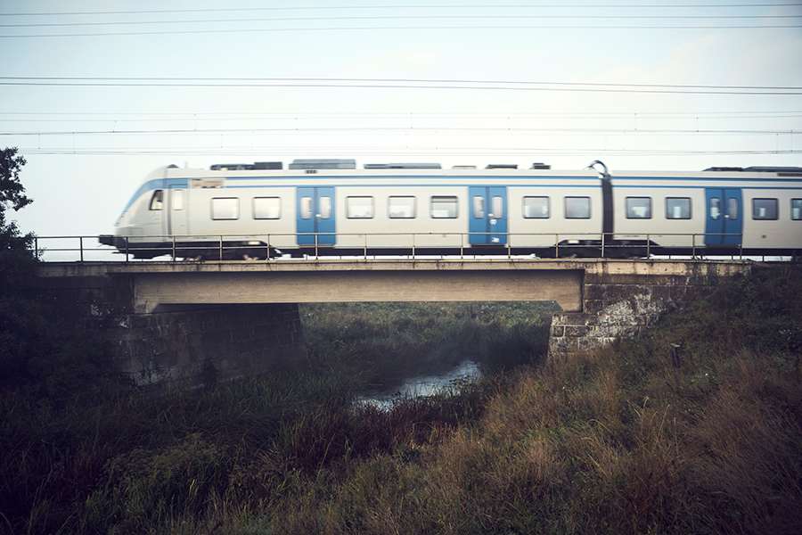 Tåg åker på en bro över en å.