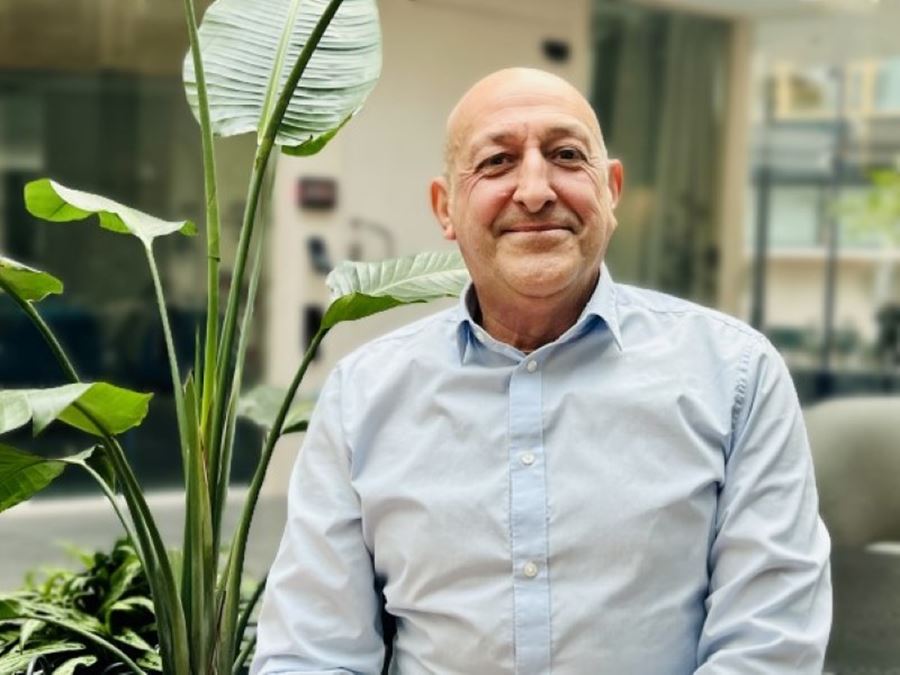 En man i ljusblå skjorta ler mot kameran