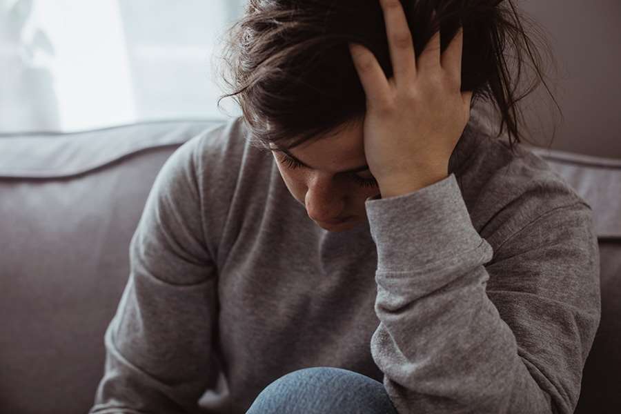 Ett barn som håller för ansiktet och tittar neråt.