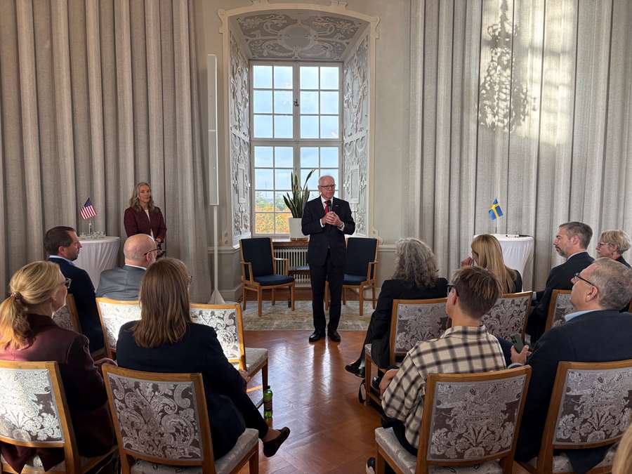 En man står framför en publik som sitter på stolar.