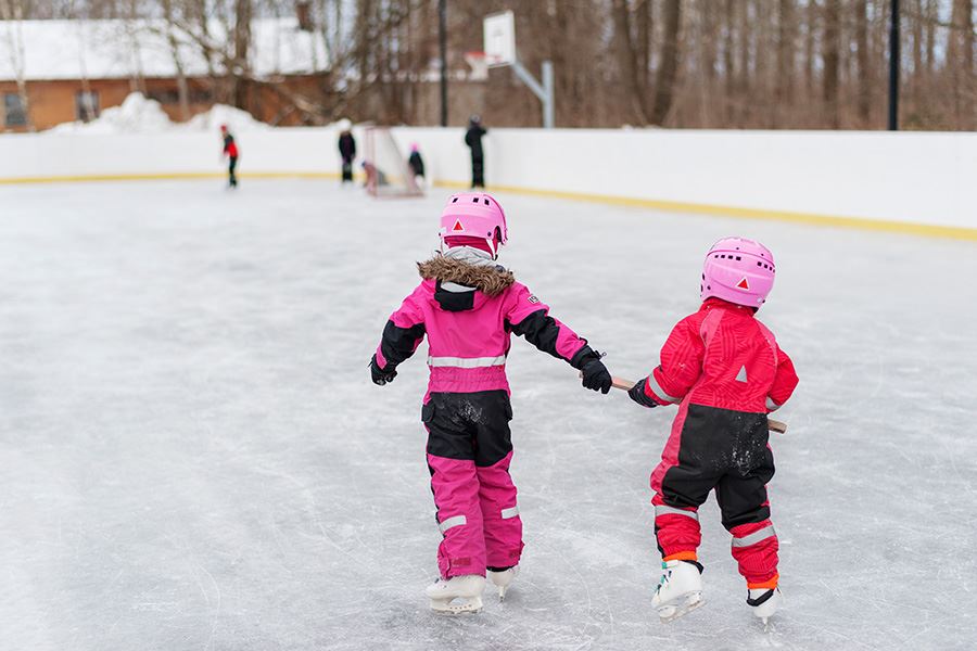Barn åker skridskor utomhus på spolad is