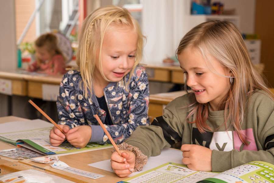 Två barn med skolböcker i klassrum