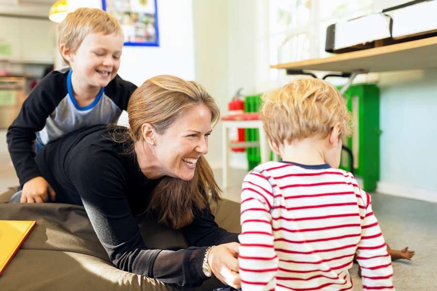 Förskolepedagog som leker med två barn.