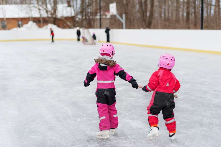 Två barn åker skridskor på en skridskobana.