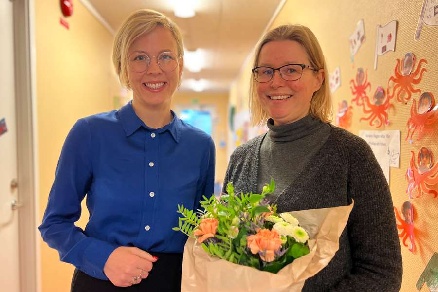 Två leende kvinnor, en håller i en bukett
