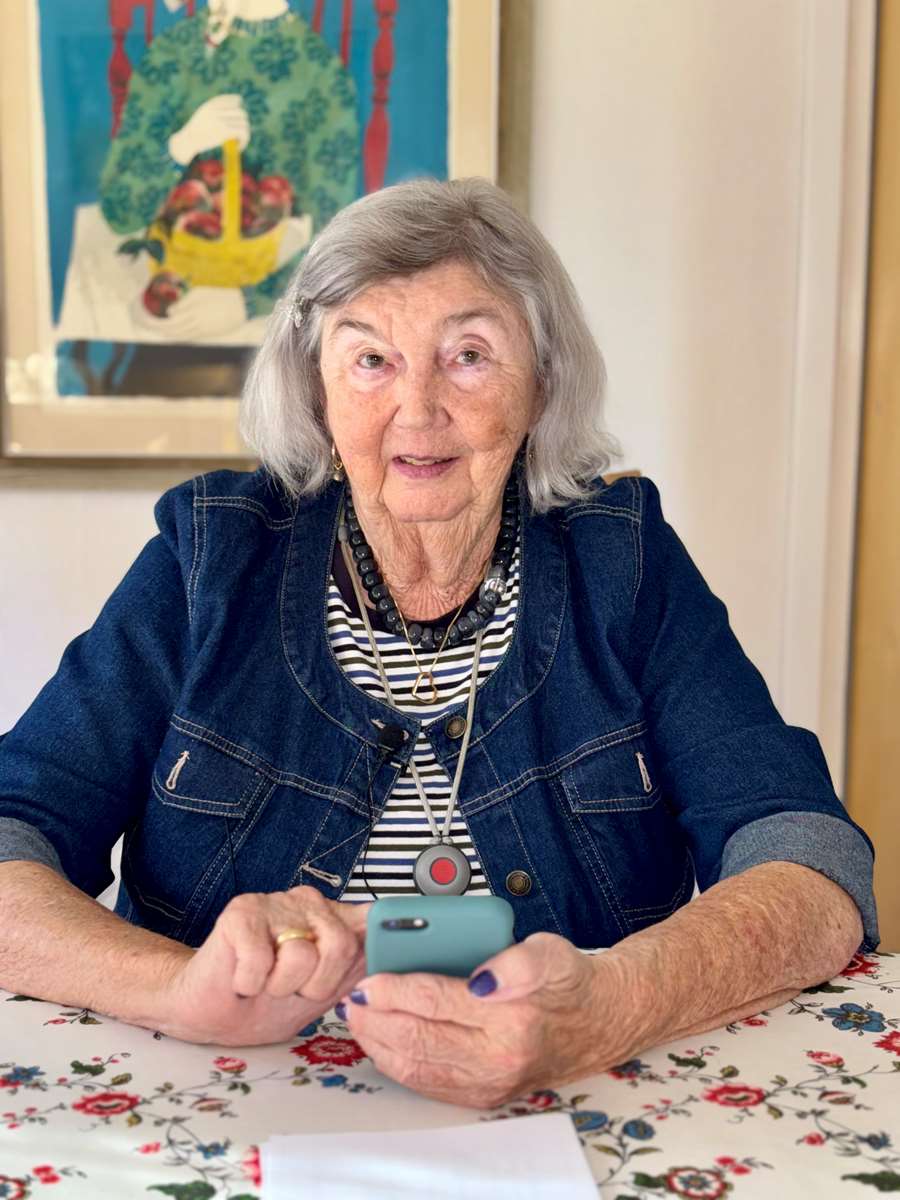 Kvinna sitter vid bord med sin telefon i handen