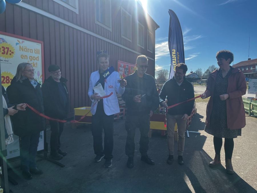 Några personer klipper ett rött band utanför ett hus.