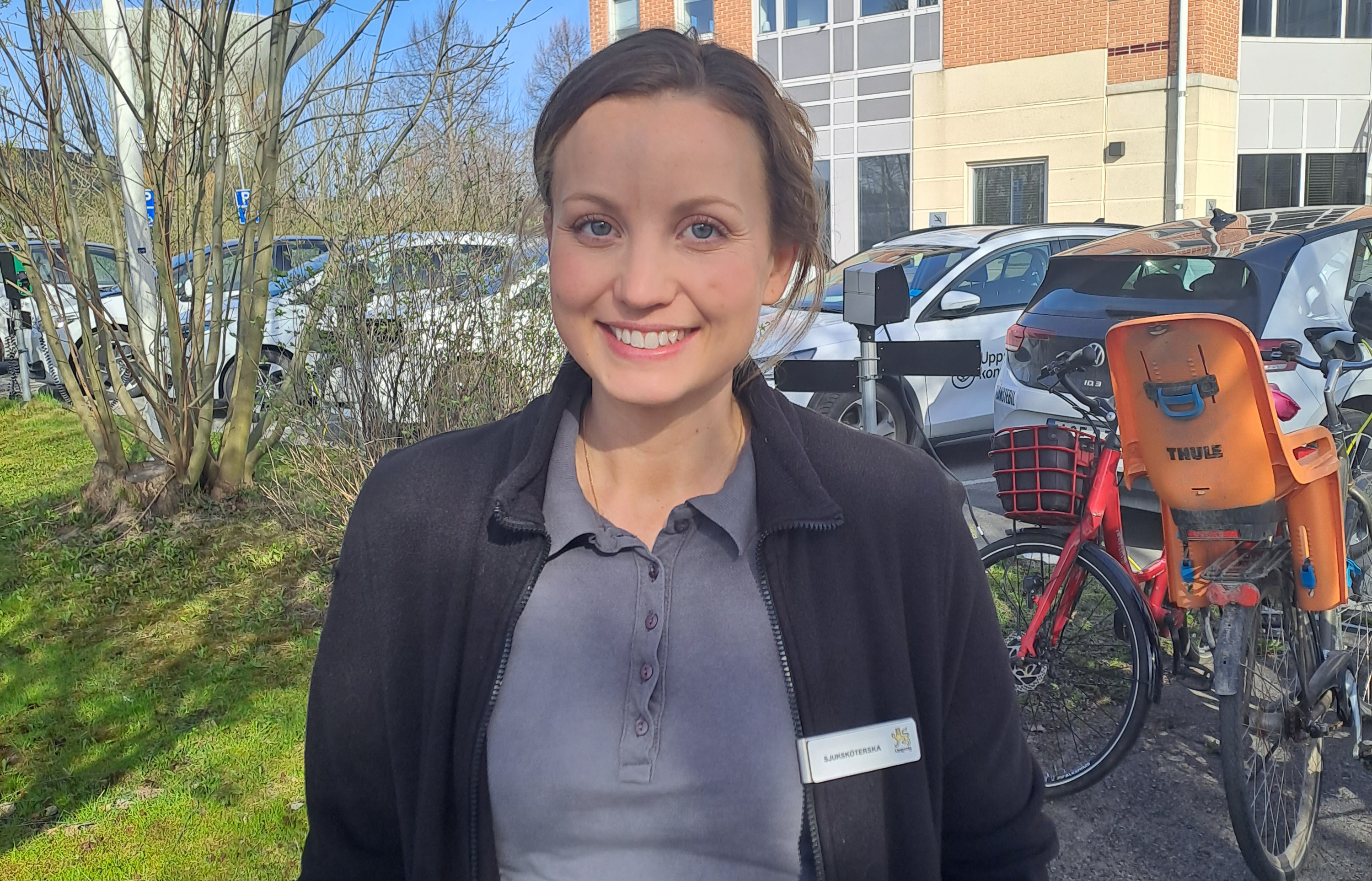 Kvinna i kommunala kläder framför ett hus