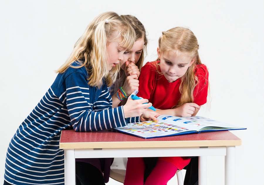 Tre flickor tittar i en kartbok
