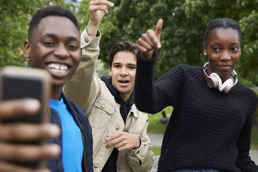 Tre ungdomar tar en bild på sig själva med en mobiltelefon
