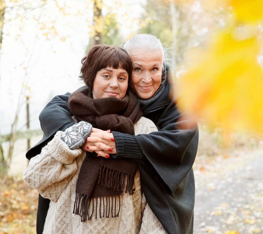 Äldre kvinna kramar yngre kvinna
