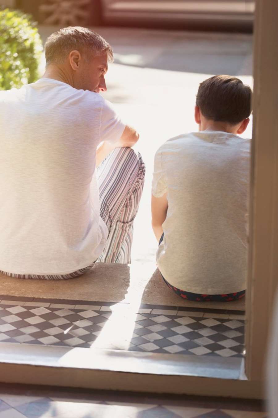 En man och en pojke i tonåren sitter på en trappa och pratar. Foto: Caiaimage