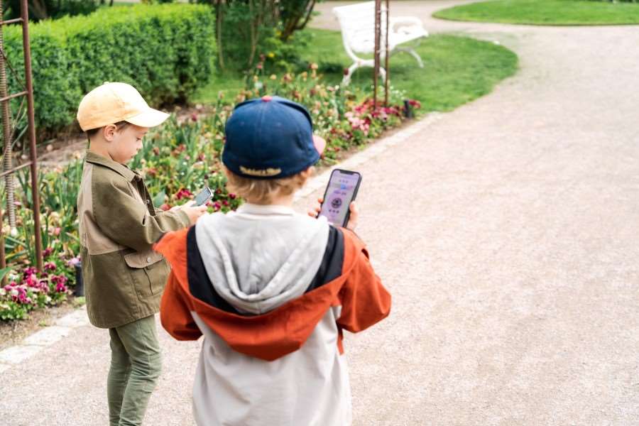 Två barn med mobiltelefoner i en park