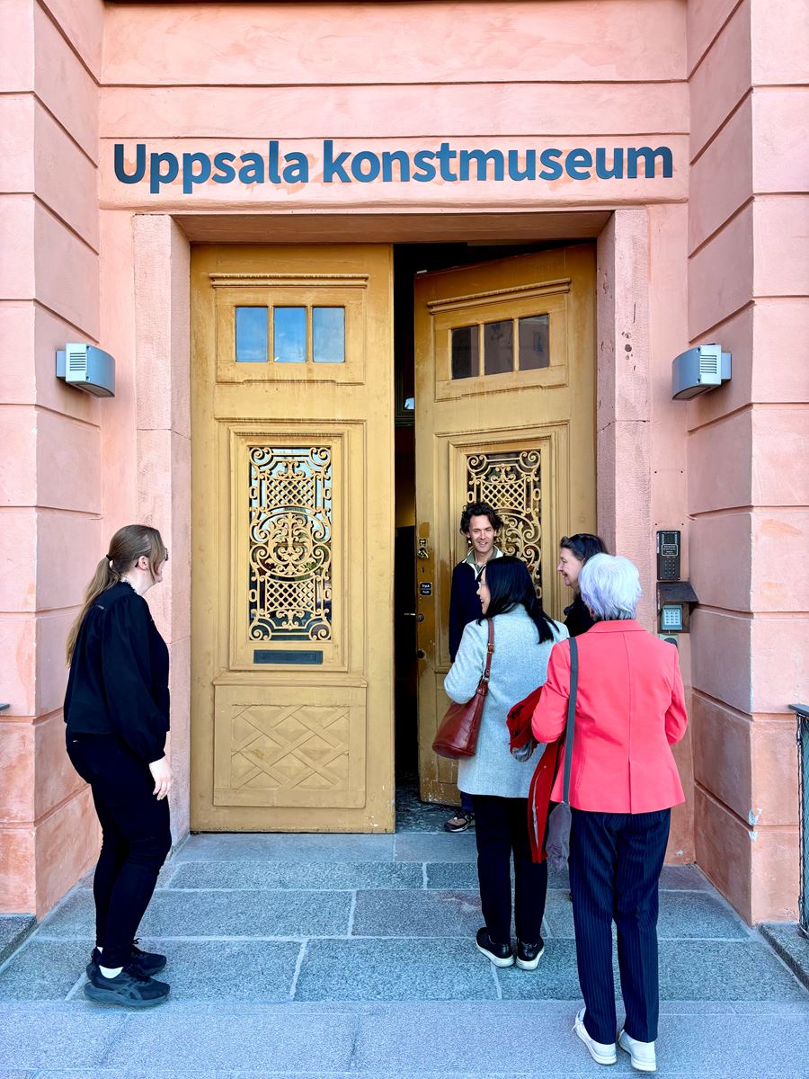 tre kvinnor går in genom en dörr som en man håller upp. Ovanför dörren står det Uppsala konstmuseum