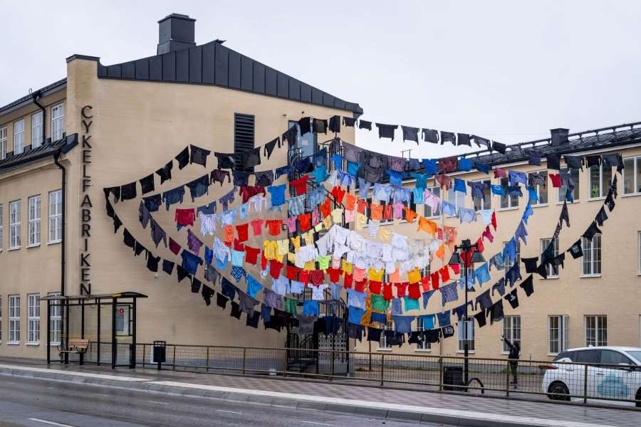 Skjortor hänger på linor mellan husfasader. Fotografi.