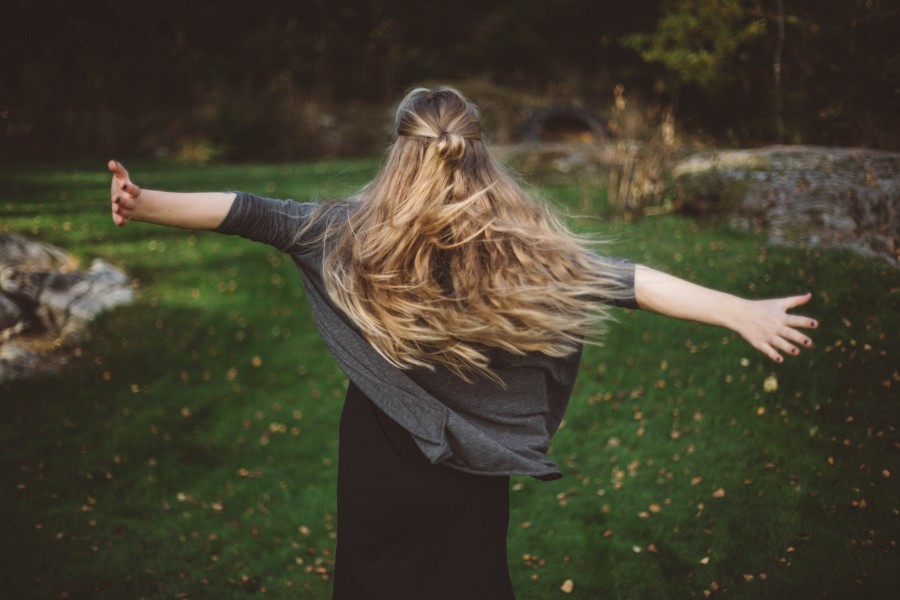 Kvinna med långt hår slår ut med händerna. Kvinnan syns bakifrån. Foto: Johnér bildbyrå