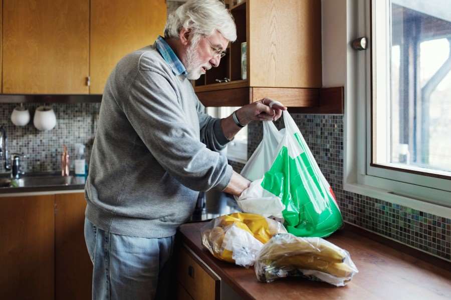 Äldre man som plockar upp matvaror på diskbänken
