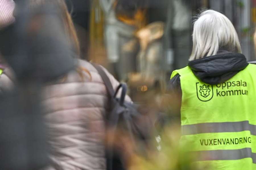 En vuxen person i reflexväst med texten vuxenvandring på ryggen.