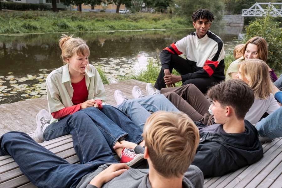 Flera ungdomar umgås tillsammans på en brygga vid vattnet.