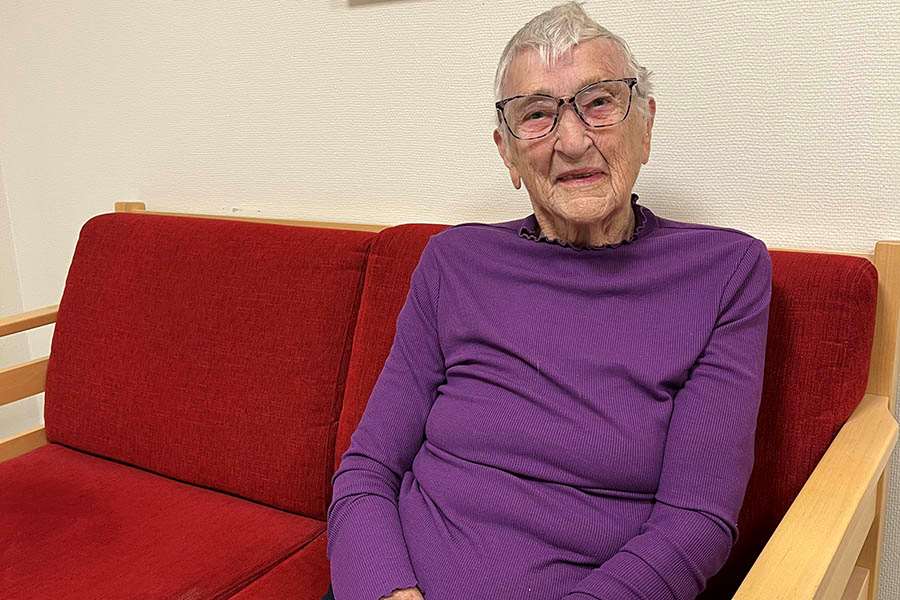 Kvinna i lila tröja sitter i en röd soffa