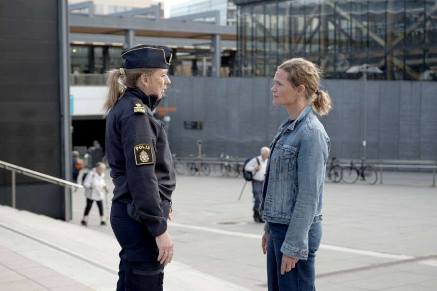 En polis och en tjänsteperson från Uppsala kommun pratar med varandra utomhus