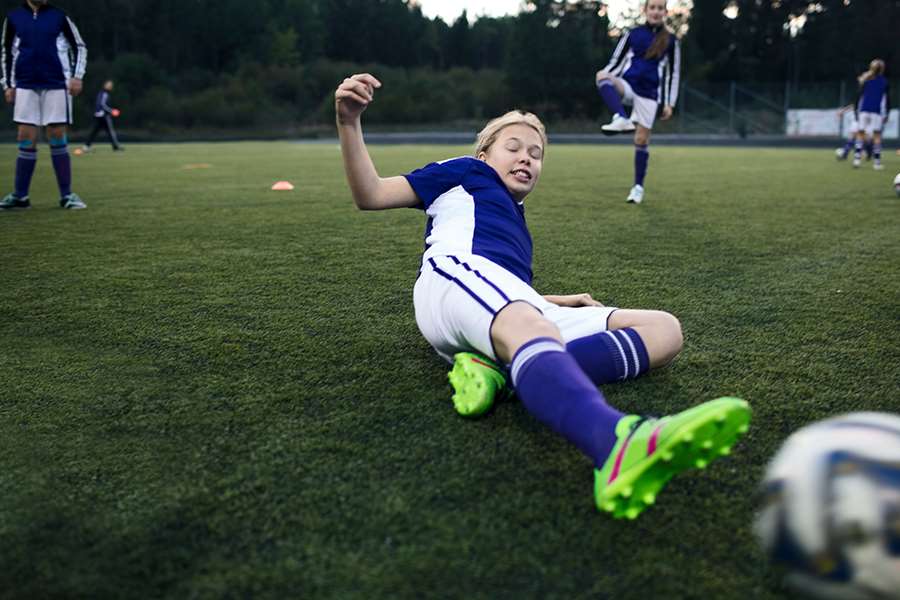 Tjej iförd matchställ gör en glidtackling mot en fotboll.