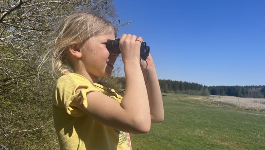 En ung tjej kollar någonting med kikare