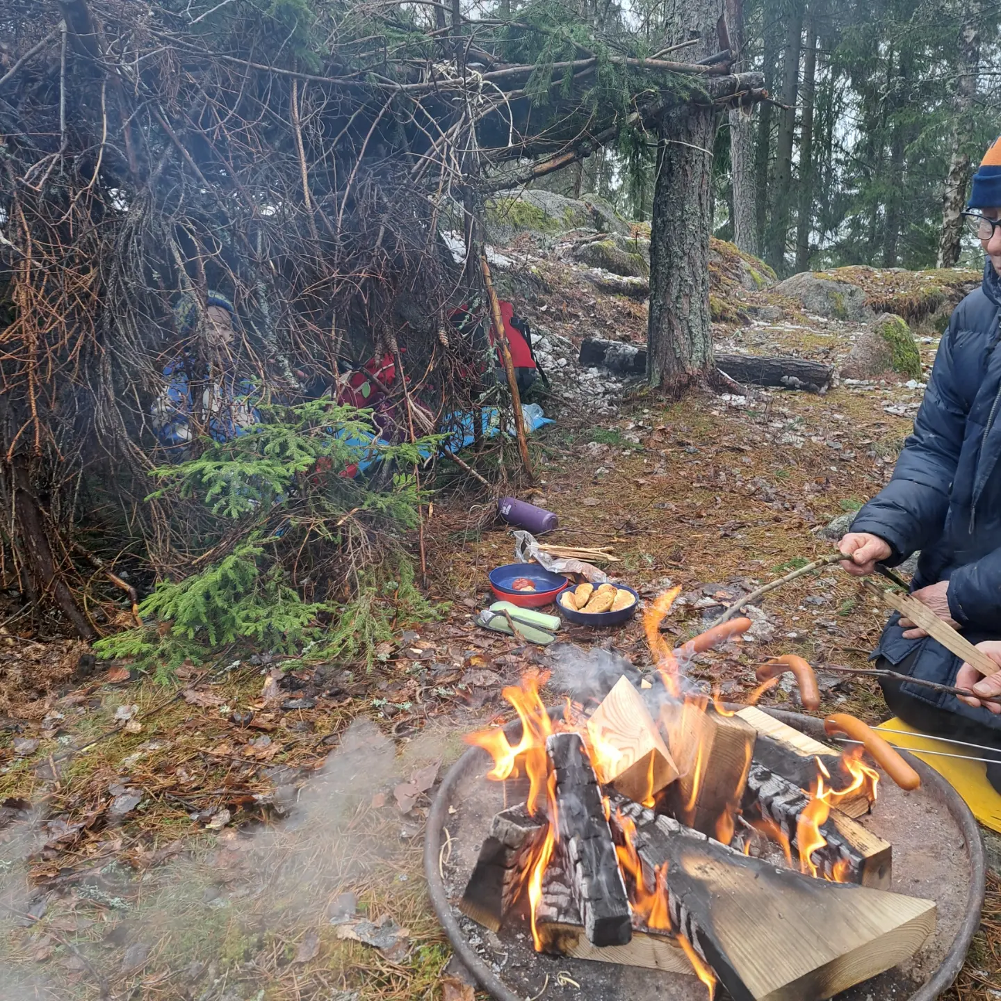 En person grillar korv vid elden