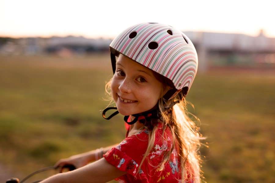 Barn med cykelhjälm ler och tittar in i kameran