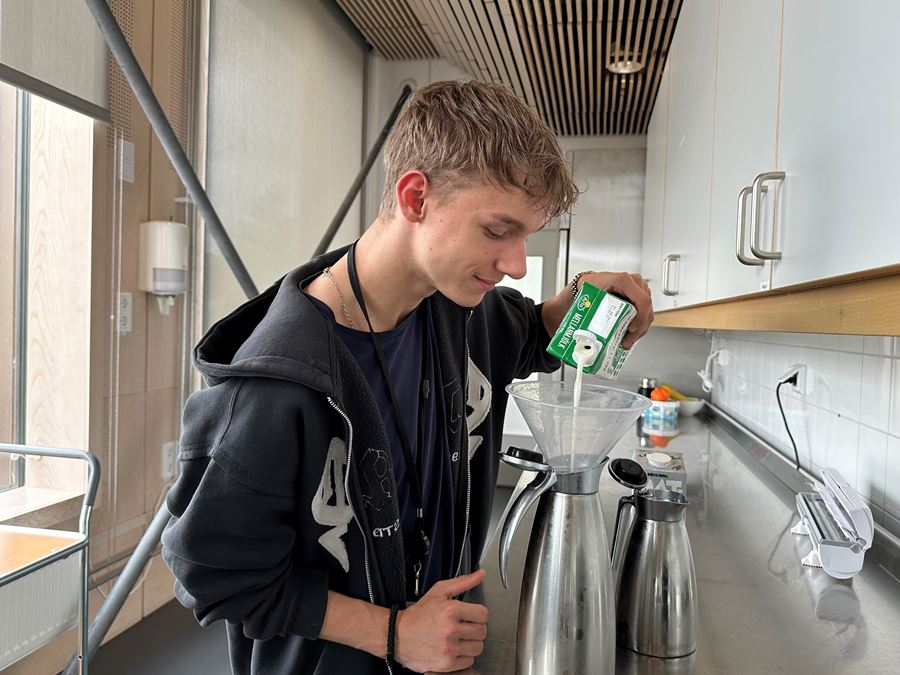En elev som häller upp mjölk i en mjölkkanna