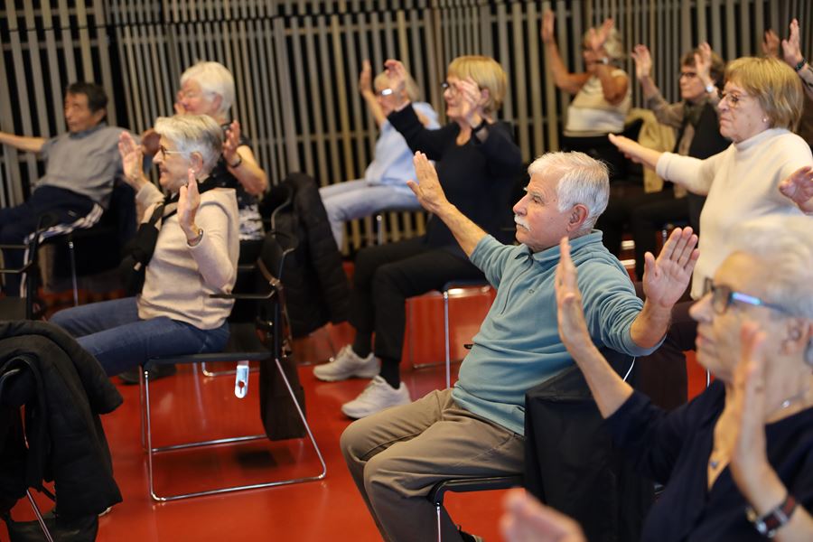Människor på stolar håller upp armarna