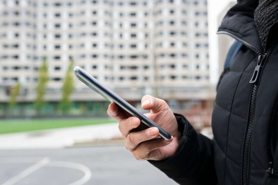 En person håller i en mobiltelefon och knappar på skärmen.