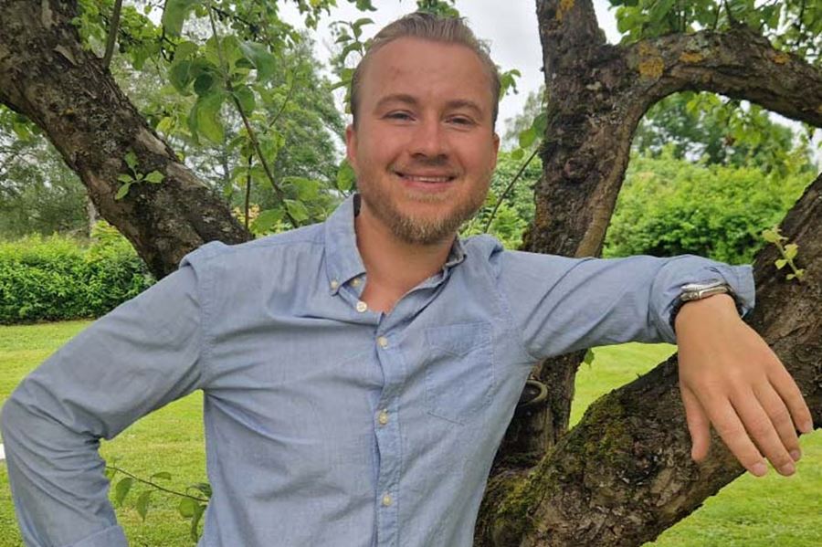 En man i blå skjorta vid ett träd