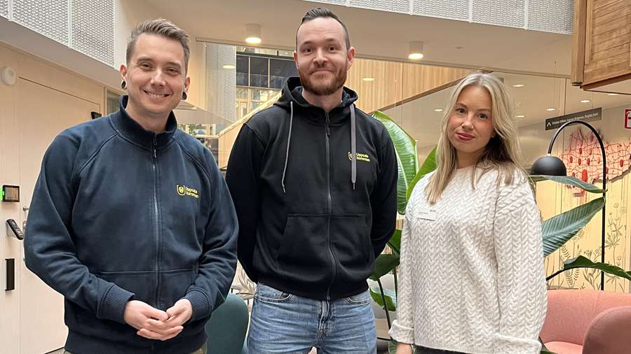 Tre personer ler in i kameran